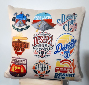A picture of a handcrafted cushion, featuring the t-shirt designs from prior Desert Bus for Hope events.