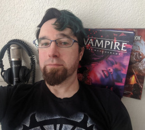 A photo of Jacob with a microphone and RPG books.