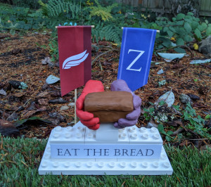 Kindness monument made out of legos. Two clay hands are holding a clay loaf of bread. The monument reads Eat the Bread.