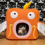 A cat sitting in a cube designed to look like a Magikarp.