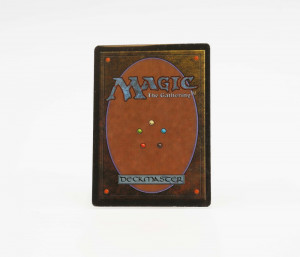 A classic, original run Magic: the Gathering card back. It features a brown oval on a lightly golden background, and a pentagram made of small dots representing each of the card colors (e.g. blue or white).