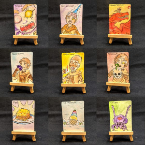 A display of nine cards, each with unique art, displayed on tiny little wooden easels.