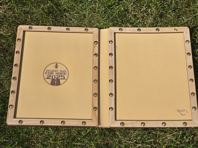 Inside the book, bordered with 1/4 inch laminated ash strips that maintain access to the chicago screws
The leather is branded with the Desert Bus 2025 logo and includes a small bee and marmot to see what you're up to
