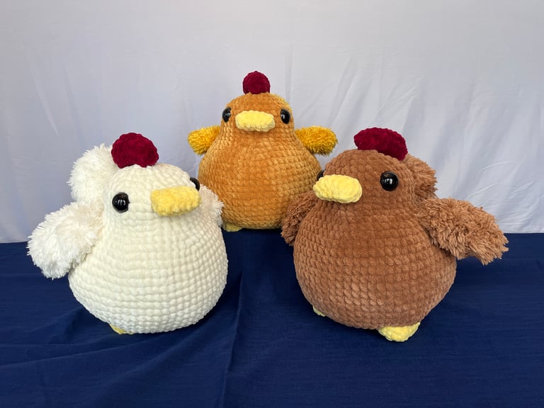 From left to right, the white chicken, golden chicken, and brown chicken are huddled together.