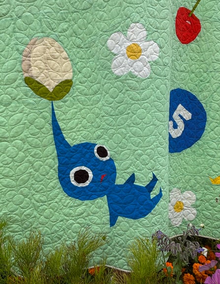 A close up of the corner with the blue Pikmin with some purple flowers and some green ferns in front of it.
