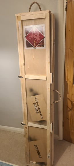 A Picture of a plywood crate with rope handles. At the top is the Shinra Electric Power Company logo and lower down is reads "Siezed by authority of SOLDIER" and "Evidence"