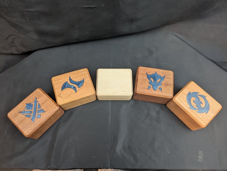 The set symbols for the 4 Tarkir sets in Magic so far, engraved and then epoxied on the lid of each deck box.
