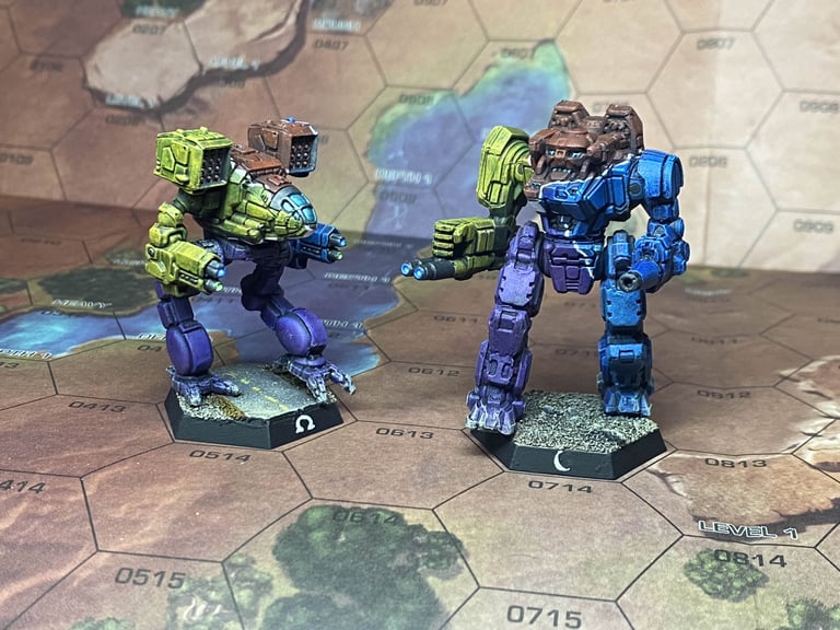 A Timber Wolf and an Executioner Omnimech painted in Unbound yellow, red, blue, and purple on a desert map
