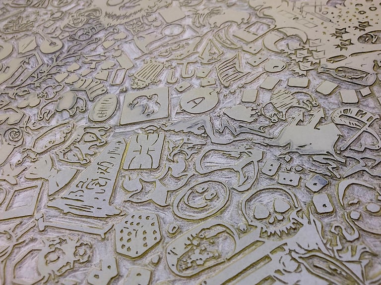 A part of the large linoleum block used to print the backdrop for the eventual cards. The block itself is about 11x16 inches, with 146 little icons representing each of the jokers filling the space. The linoleum block is carved by hand for relief printing.