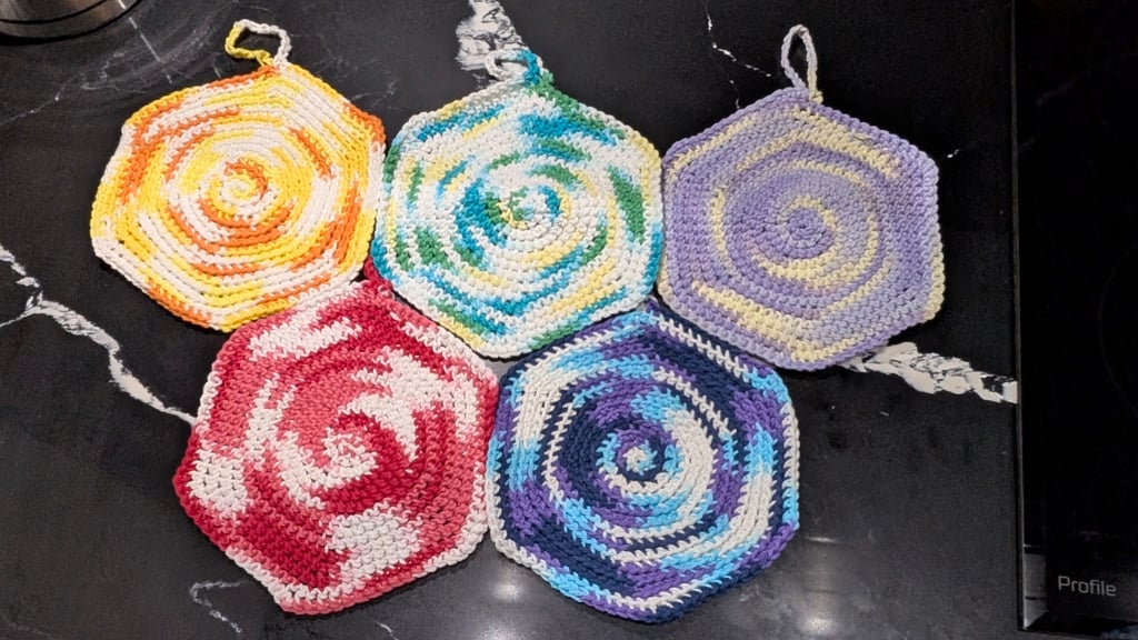 Just the Trivets. 
They have a single crochet chain loop at the end of the piece for hanging off hooks or faucet bits.
The pattern is all single crochet, but only using one side of the loop on every rotation to create two unique sides.

Top: Dawn Guard, Omega, Zeta
Bottom: Alpha Flight, Night Watch
