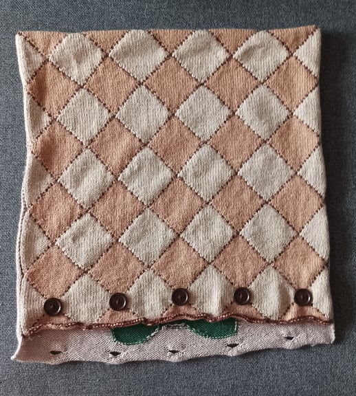 A photo of the cushion cover on the diamonds side without the cushion insert, placed on a grey background.
