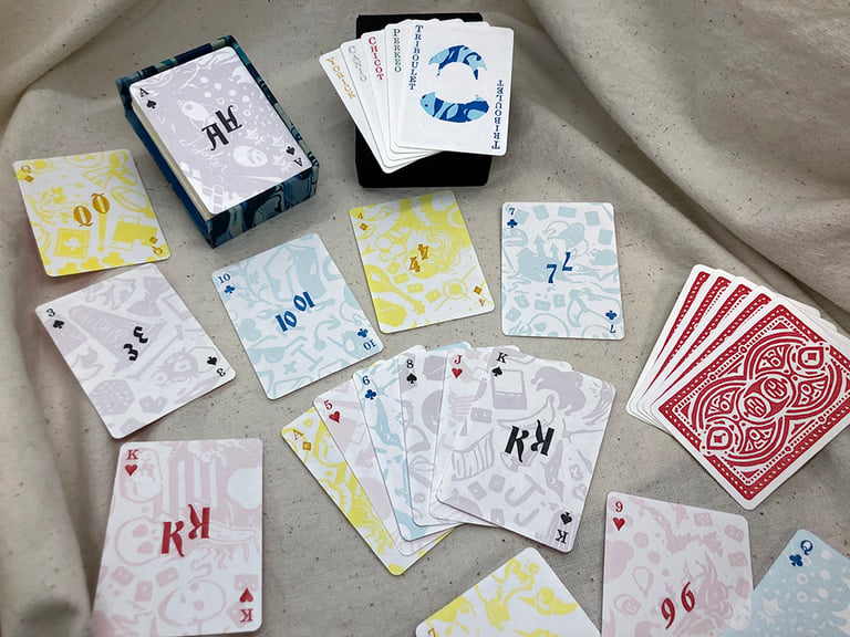 A handful of the cards, showing several faces, the jokers, the box, and the back sides. The backs of the cards are printed with the pattern of some of the default Balatro decks.